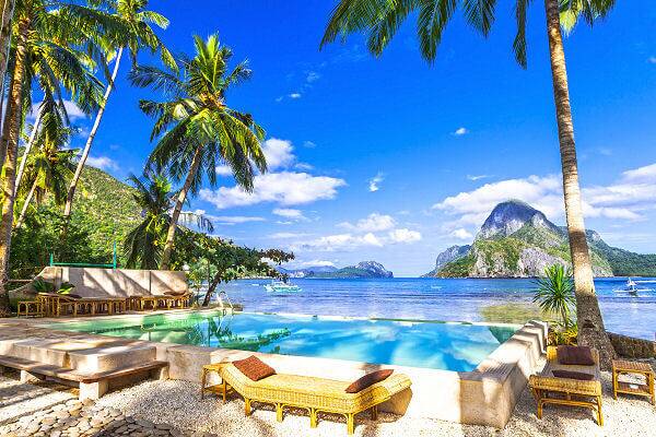 Tropisches Resort mit Pool am Meer auf Palawan, umgeben von Palmen und Kalksteinfelsen auf den Philippinen.