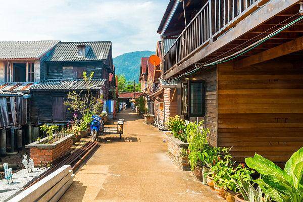 Gasse in Lanta Old Town auf Koh Lanta mit traditionellen Holzhäusern auf Stelzen und Pflanzen entlang des Weges