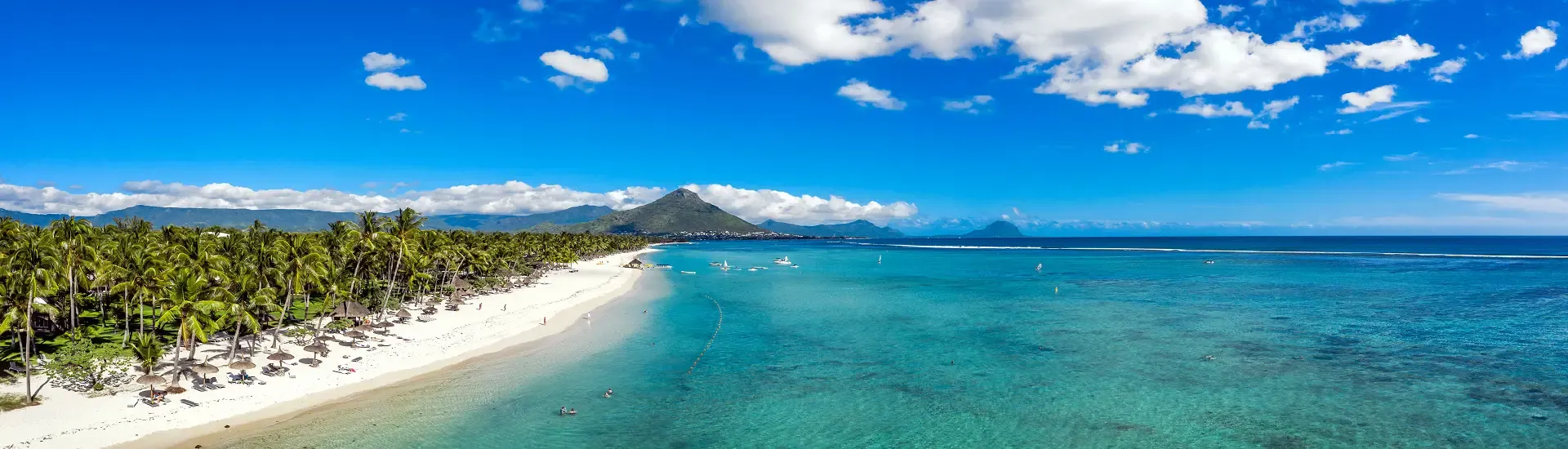 Strand auf Mauritius mit Palmen, türkisfarbenem Meer und Berglandschaft
