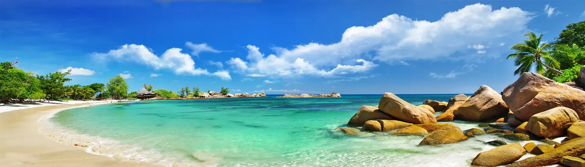 Seychellen-Strand mit Granitfelsen, Palmen und türkisfarbenem Meer