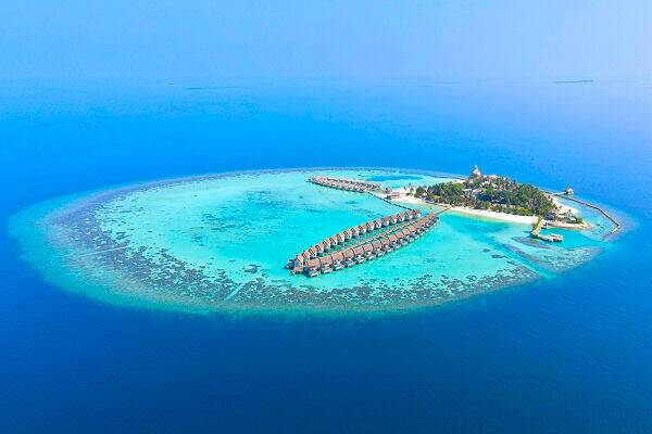 Luftaufnahme eines Inselresorts auf den Malediven mit Wasserbungalows im türkisfarbenen Meer