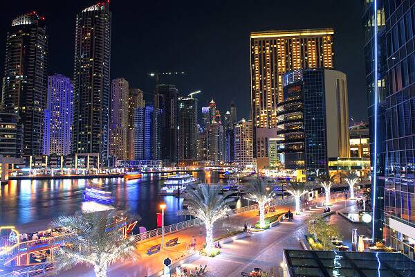 Dubai Marina bei Nacht mit beleuchteten Hochhäusern und Booten