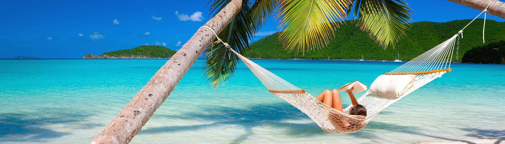 Hängematte unter Palmen an einem weißen Sandstrand im Indischen Ozean mit türkisblauem Meer