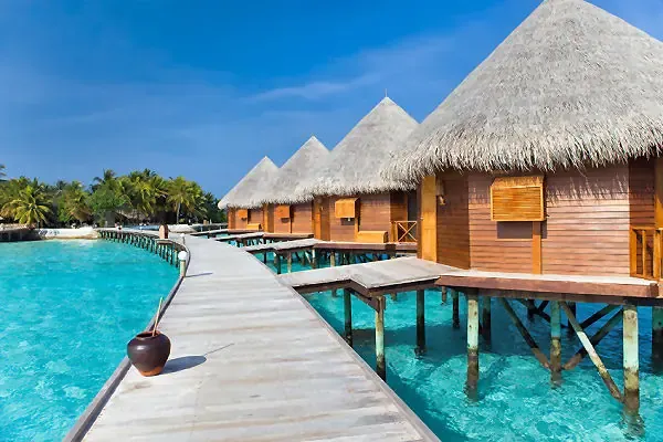 Holzstege mit Wasser­villen über türkisblauem Meer auf den Malediven – AsiaGo