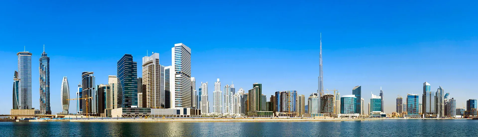 Panoramablick auf die Skyline von Dubai mit modernen Hochhäusern und dem Burj Khalifa bei blauem Himmel