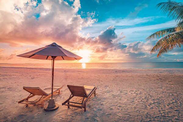 Strand mit Liegestühlen und Sonnenuntergang als Symbol für Inselwelten in Asien