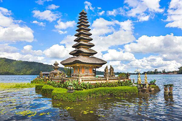 Tempel im See auf Bali in Indonesien bei sonnigem Himmel, umgeben von Wasser und Bergen