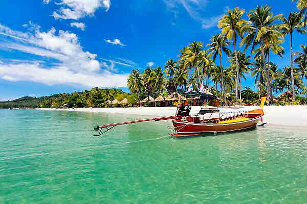 Longtail-Boot vor einem tropischen Strand in Thailand