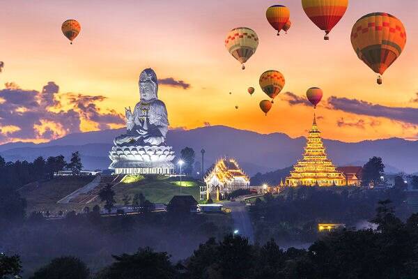 Tempel, Buddha-Statue und Heißluftballons über einer Berglandschaft als Beispiel für die kulturelle und landschaftliche Vielfalt Asiens