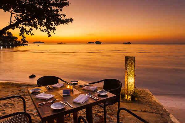 Strandrestaurant am Bang Niang Beach in Khao Lak mit gedecktem Tisch direkt am Meer bei Sonnenuntergang