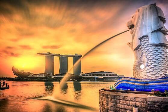 Der Merlion, das Wahrzeichen von Singapur, mit Blick auf das Marina Bay Sands Hotel und die Skyline der Marina Bay bei Sonnenuntergang.