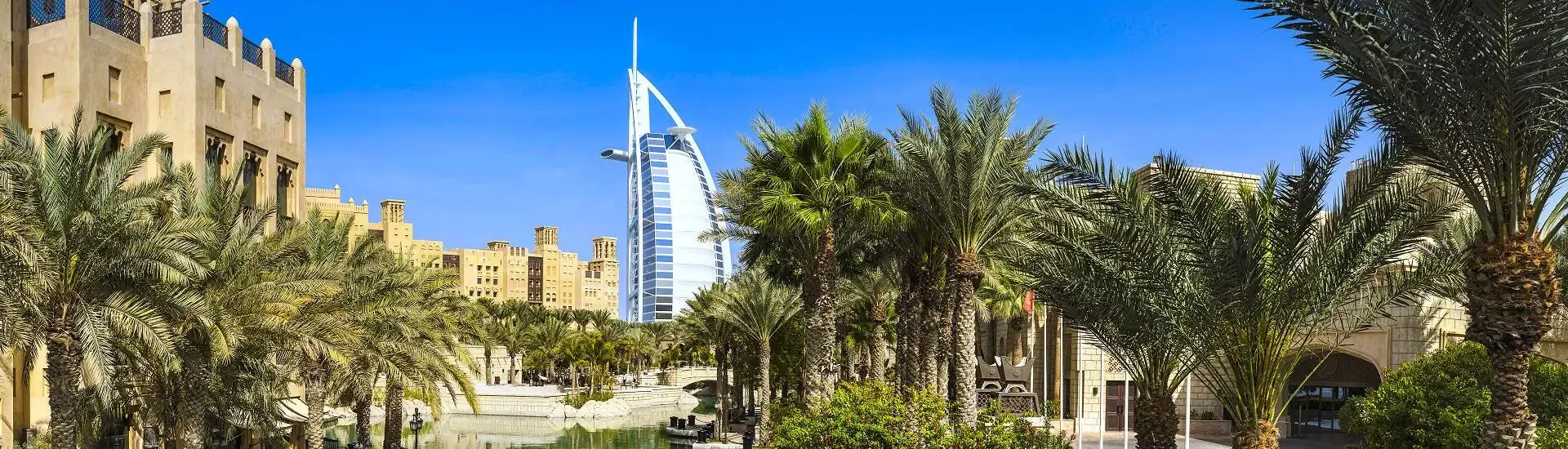 Burj Al Arab und traditionelle Gebäude zwischen Palmen in Dubai – AsiaGo