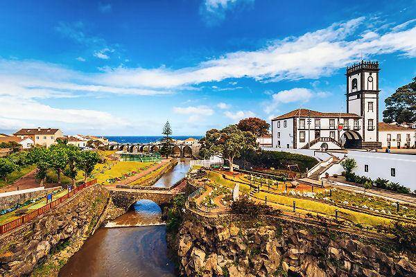 Küstenstadt auf den Azoren mit Brücke, Kirche und grüner Landschaft