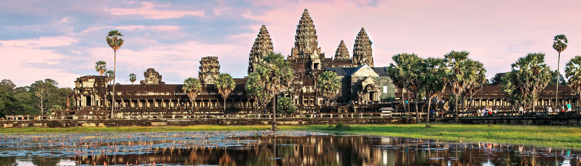 Panoramablick auf Angkor Wat in Siem Reap, Kambodscha, mit den markanten Tempeltürmen, Palmen und Spiegelungen im Wasser vor der historischen Tempelanlage.