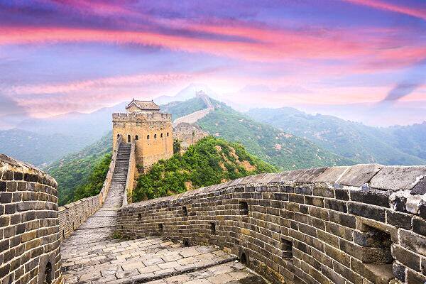 Blick auf die Große Mauer in China bei Sonnenuntergang mit Bergen im Hintergrund