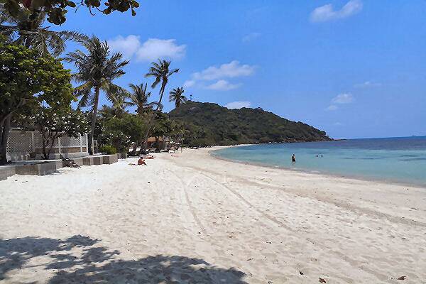 Der Haad Rin Beach auf Koh Phangan in Thailand mit weißem Sandstrand, Palmen und türkisblauem Meer an der Küste der Insel.