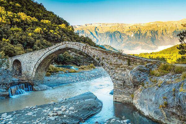 Steinbrücke über Fluss in bergiger Landschaft in Albanien