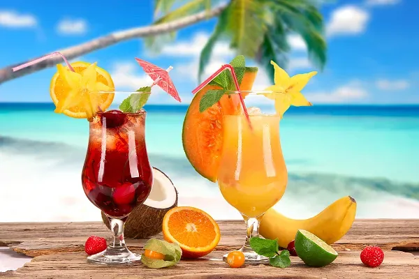 Fruchtcocktails am Strand mit türkisfarbenem Meer und Palmbaum - Last-Minute-Urlaub in Thailand.