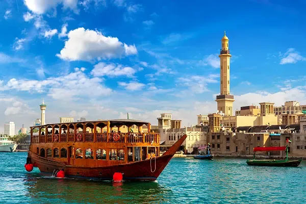 Traditionelles Dhow-Boot auf dem Dubai Creek mit Blick auf Deira und historische Gebäude am Wasser