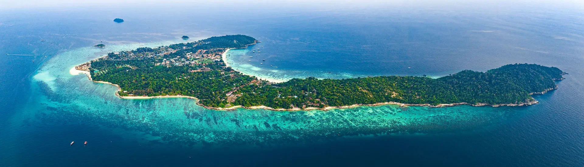 Koh Lipe in Südthailand mit türkisfarbenem Wasser, hellem Sandstrand und dicht bewaldeter Insel