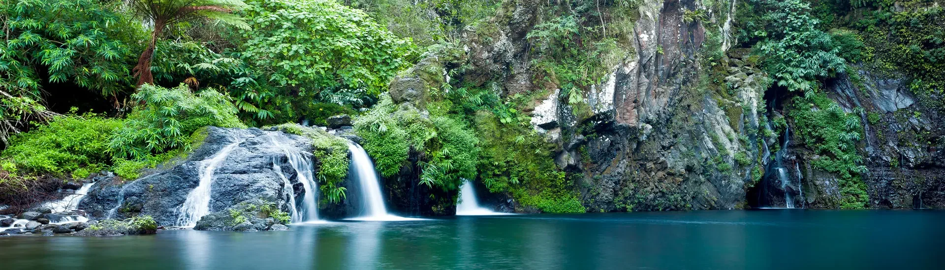 Wasserfall auf La Réunion in dichter tropischer Vegetation mit Felsen und natürlichem Becken