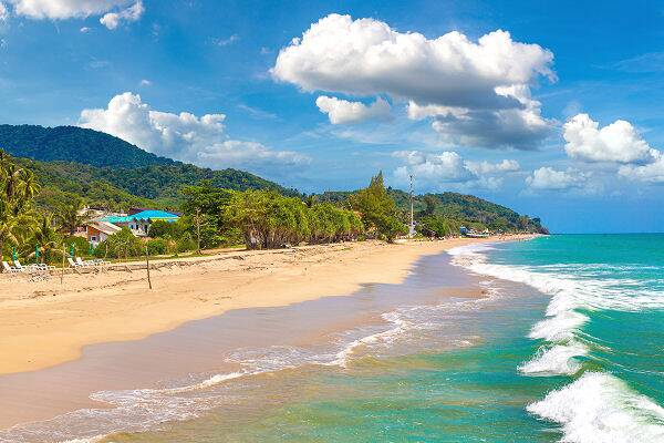 Der Klong Nin Beach auf Koh Lanta in Thailand mit langem Sandstrand, türkisblauem Meer, tropischer Vegetation und bewaldeten Hügeln im Hintergrund.