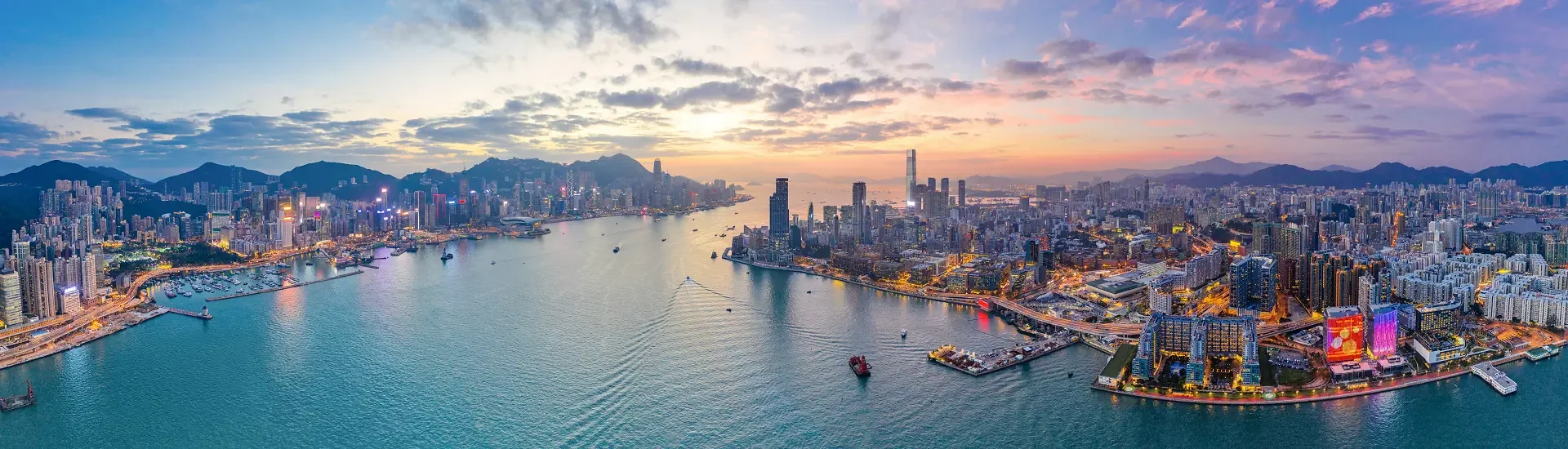 Panoramablick auf den Hafen von Hongkong mit Skyline und Hochhäusern bei Sonnenuntergang