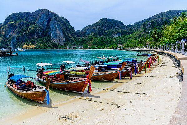 Traditionelle Longtail-Boote am Pier der Phi Phi Inseln mit Kalksteinfelsen im Hintergrund