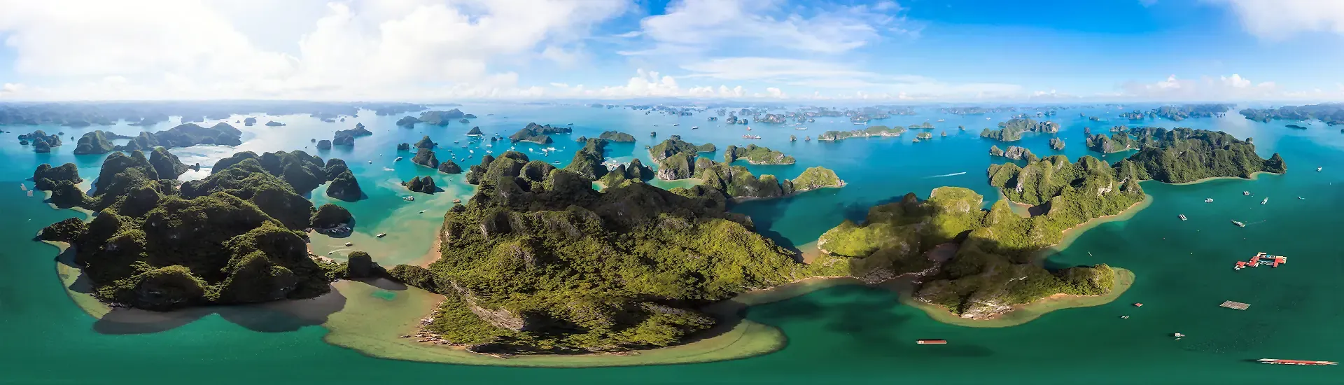 Luftaufnahme der Halong-Bucht in Vietnam mit grünen Kalksteininseln und Booten