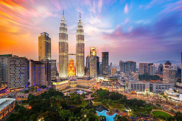 Petronas Towers in Kuala Lumpur – Malaysia Reisen mit AsiaGo Skyline von Kuala Lumpur in Malaysia bei Sonnenuntergang mit den Petronas Twin Towers im Vordergrund