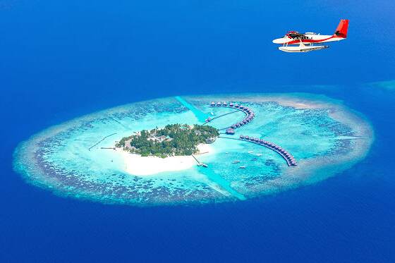 Tropische Insel der Malediven mit Overwater-Villen und Wasserflugzeug über türkisblauem Meer