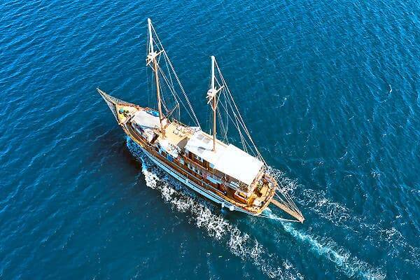Holzsegelboot auf blauem Meer vor den Kykladen, Symbolbild für Segelurlaub in Griechenland