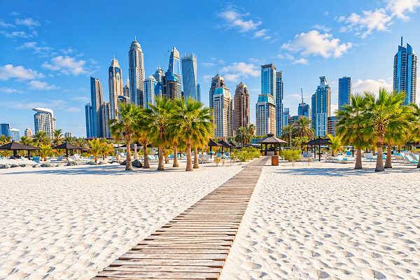 Sandstrand mit Palmen vor der Skyline von Dubai