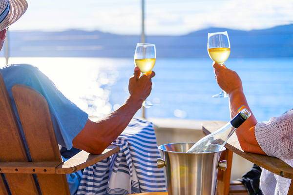 Zwei Reisende stoßen mit Weingläsern auf einem Flussschiff an, Symbol für Flusskreuzfahrten