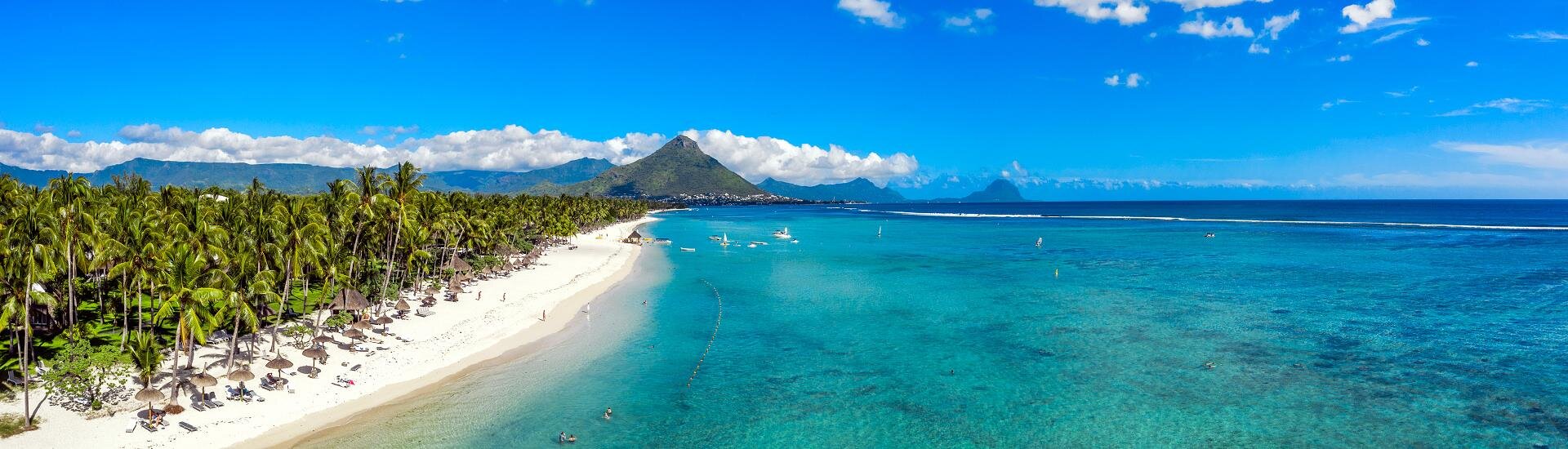 Palmenstrand mit türkisfarbener Lagune und Blick auf die Küste von Mauritius