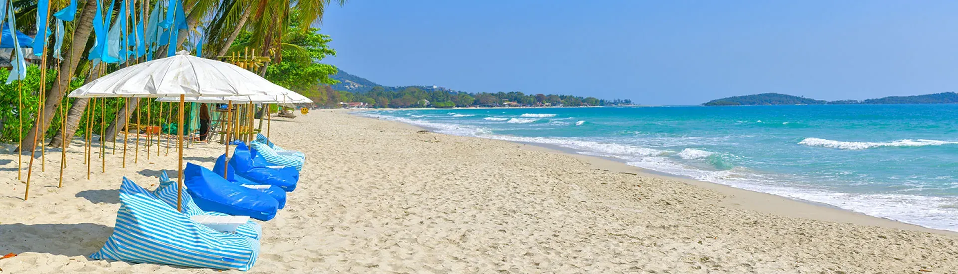 Breiter Sandstrand in Khao Lak mit Palmen und Liegen am Meer