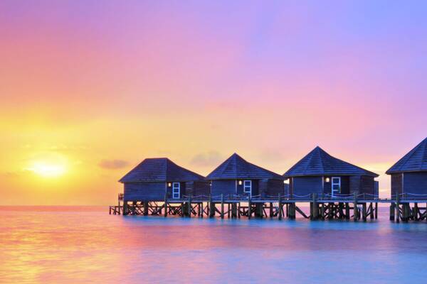 Wasserbungalows auf den Malediven bei Sonnenuntergang