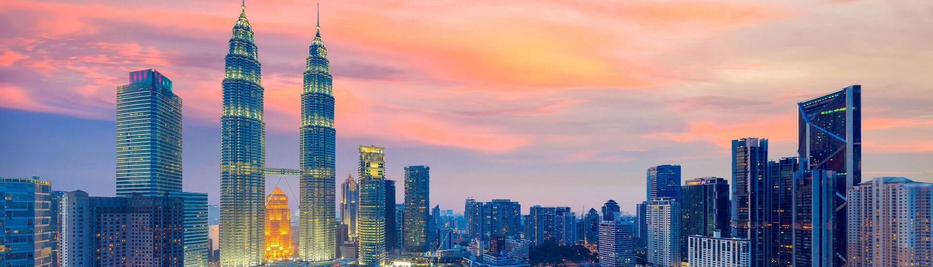 Skyline von Kuala Lumpur bei Sonnenuntergang mit den Petronas Twin Towers und modernen Hochhäusern in Malaysia.