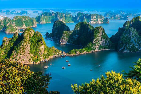 Blick auf die Halong-Bucht in Vietnam mit grünen Kalksteininseln und Booten