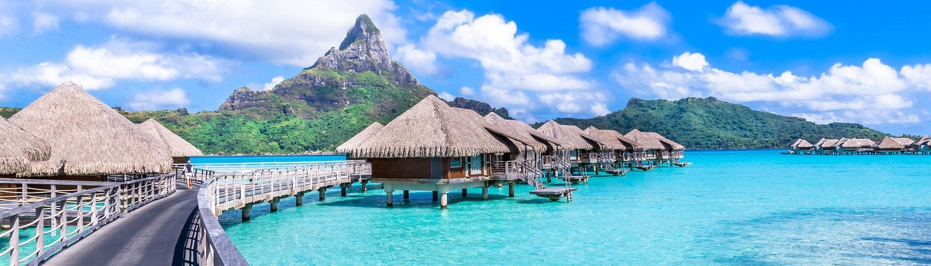 Overwater-Bungalows in einem tropischen Inselresort mit türkisfarbenem Wasser – typisches Reiseziel für Luxusreisen im Indischen Ozean