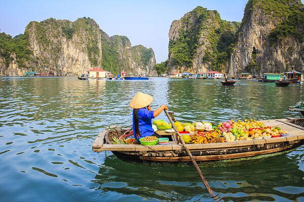 Frau im Boot auf der Halong-Bucht mit Felsen im Hintergrund, Symbol für Vietnam Reisen