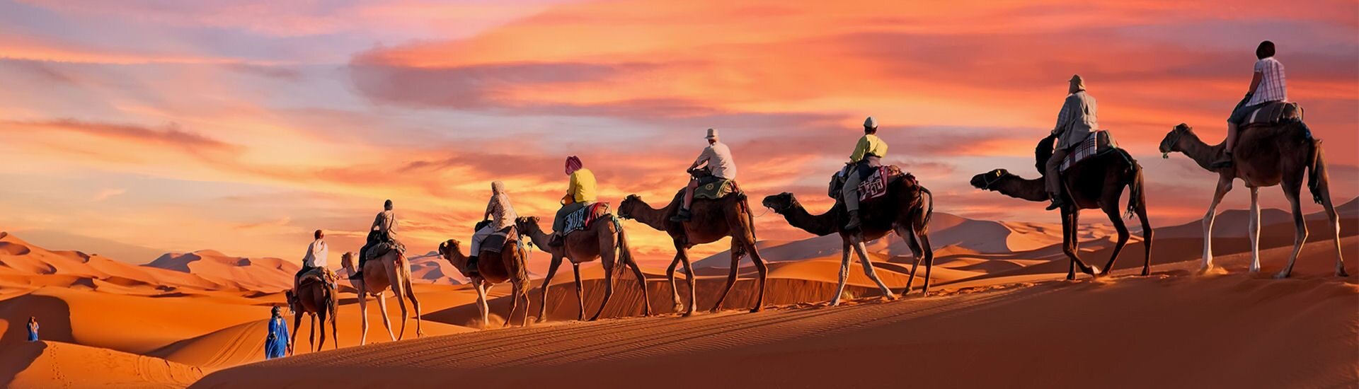 Wüstensafari auf Kamelen in den Sanddünen der Vereinigten Arabischen Emirate bei Sonnenuntergang