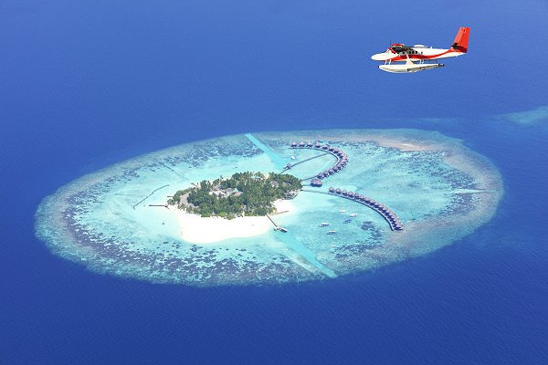 Tropische Insel in türkisfarbener Lagune auf den Malediven mit Wasserbungalows