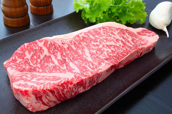 Rohes Kobe-Rindfleisch mit feiner Marmorierung auf einer schwarzen Platte, typisch für die japanische Küche.