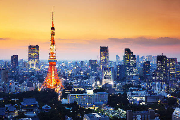 Beleuchtete Skyline von Tokio bei Sonnenuntergang mit dem Tokyo Tower und modernen Wolkenkratzern in Japan.