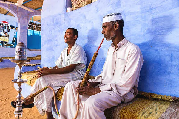 Ägypten Nilkreuzfahrt – Einheimische in Assuan in traditioneller Kleidung mit Shisha