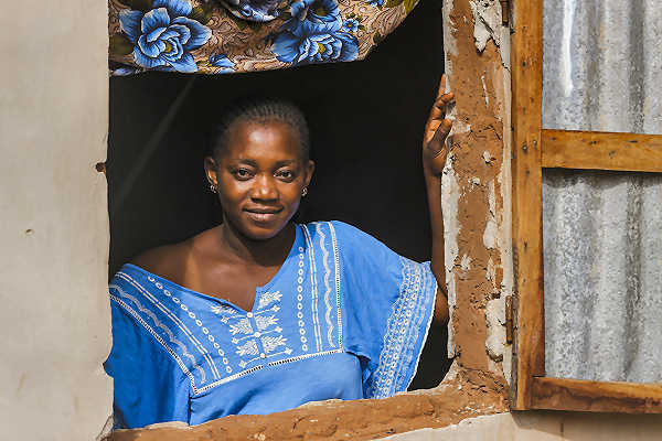 Senegal Reisen – Begegnungen & authentische Einblicke Senegalesische Frau in traditioneller Kleidung blickt aus einem Fenster – authentische Eindrücke aus Westafrika | AsiaGo