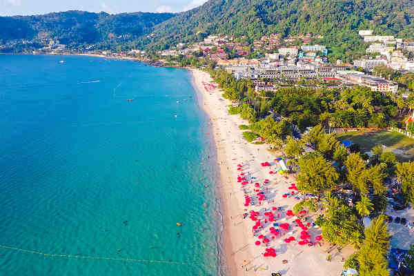 Blick auf den weißen Sandstrand und das türkisfarbene Wasser des Patong Beach auf der Insel Phuket, Thailand