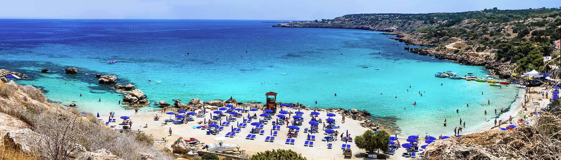 Konnos Bay auf Zypern – Sandstrand mit Sonnenschirmen, türkisblaues Wasser und Badegäste in einer malerischen Bucht