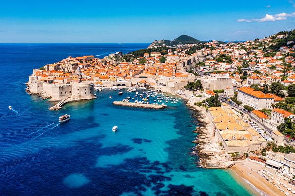 Luftaufnahme der historischen Altstadt von Dubrovnik, Kroatien, mit Stadtmauer, Hafen und türkisblauem Meer